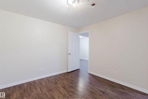 Room featuring wood-finish flooring, light-toned walls, white trim, and a white interior door - 1686 Tompkins Wynd Nw, Edmonton, AB - Indoor Photo Showing Other Room