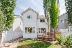 Two-story white siding residence featuring a multi-level wood deck, a partial grass yard, and a gravel-lined side yard - 