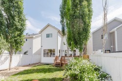 White siding exterior featuring a multi-level wood deck, a manicured lawn, and mature trees - 