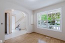 Spacious interior featuring wood-finish flooring, a large multi-pane window, an arched entryway, light-colored walls, and a staircase with carpeted treads - 1686 Tompkins Wynd Nw, Edmonton, AB  - Indoor Photo Showing Other Room 