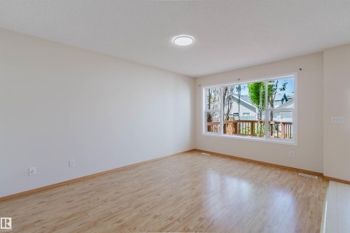 Expansive interior room featuring light wood-finish flooring, a contemporary flush-mount ceiling light, and ample natural light from a large multi-pane window - 1686 Tompkins Wynd Nw, Edmonton, AB - Indoor Photo Showing Other Room