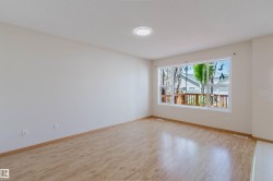 Expansive interior room featuring light wood-finish flooring, a contemporary flush-mount ceiling light, and ample natural light from a large multi-pane window - 