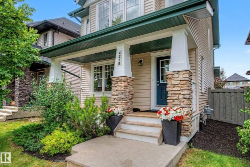 Inviting covered front porch with stone-wrapped columns and a dark blue entry door - 4218 Allan Link Link Sw, Edmonton, AB - Outdoor