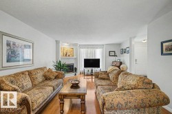 Spacious living area featuring wood-finish flooring, a corner fireplace, and ample natural light from the large window - 