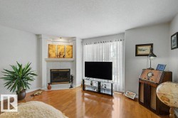 Living area featuring wood-finish flooring and a corner fireplace with a tile surround and hearth - 