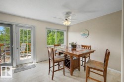 Dining area featuring wood-finish flooring, a ceiling fan with integrated lighting, and multiple windows - 