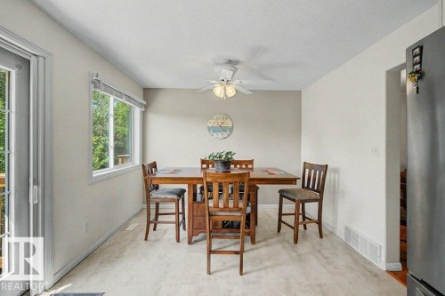 Dining area featuring light-toned walls, a large window, a ceiling fan with integrated lighting, and wood-finish flooring - #39 2419 133 Av Nw, Edmonton, AB - Indoor Photo Showing Dining Room