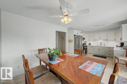 Eat-in kitchen featuring light-toned cabinetry, stainless steel appliances, a subway tile backsplash, and a ceiling fan with integrated lighting - #39 2419 133 Av Nw, Edmonton, AB - Indoor Photo Showing Dining Room