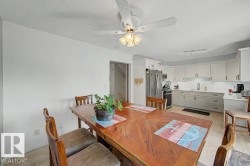 Eat-in kitchen featuring light-toned cabinetry, stainless steel appliances, a subway tile backsplash, and a ceiling fan with integrated lighting - 