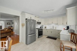 Kitchen featuring light-toned cabinetry with dark hardware, a stainless steel French door refrigerator, and a matching stainless steel range with an overhead microwave - 