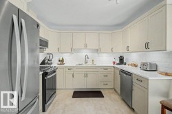 Modern kitchen featuring light-toned cabinetry, stainless steel appliances, white subway tile backsplash, white countertops, and light wood-finish flooring - 