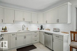 Modern kitchen featuring light-toned cabinetry with dark hardware, white subway tile backsplash, and light countertops - 