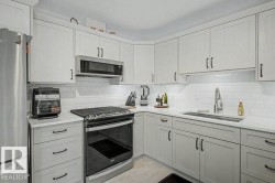 Contemporary kitchen featuring light-toned cabinetry, stainless steel appliances, a white subway tile backsplash, and a large single-basin sink with a pull-down faucet - 