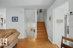 Wood-finish flooring throughout, bright white walls, and a multi-level staircase with wood treads and white risers - 