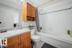 Full bathroom featuring a single vanity with wood-finish cabinetry, a light-toned countertop, and an integrated sink - 