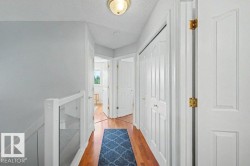 Hallway featuring wood-finish flooring, white panel doors with brass hardware, and a built-in display niche with glass shelving - 