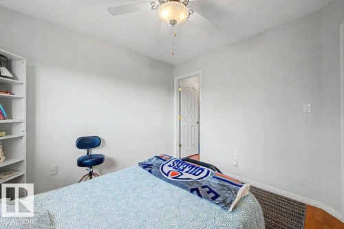 Bedroom featuring wood-finish flooring, a ceiling fan with integrated lighting, and a built-in shelving unit - #39 2419 133 Av Nw, Edmonton, AB - Indoor Photo Showing Bedroom