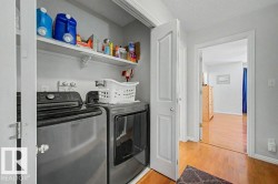 Dedicated laundry closet featuring a stacked washer and dryer, an overhead storage shelf, and a light gray wall finish - 