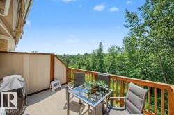 Upper-level deck featuring composite decking, wood railing, and privacy paneling, overlooking a treed landscape - 