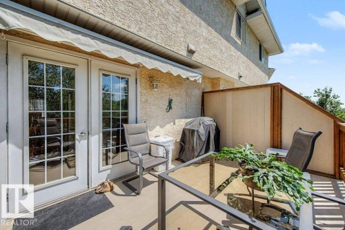 Private balcony patio featuring a textured stucco exterior, an awning, and a privacy screen - #39 2419 133 Av Nw, Edmonton, AB - Outdoor With Deck Patio Veranda With Exterior