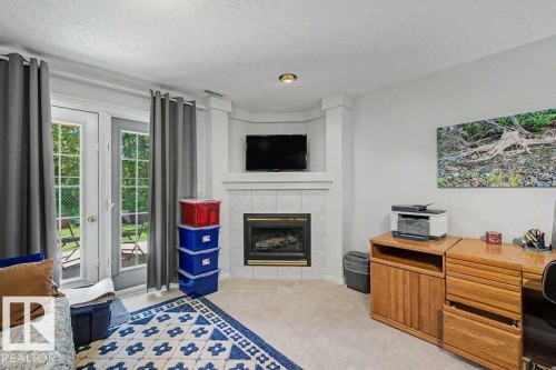 Corner fireplace with a tiled surround and mantel - #39 2419 133 Av Nw, Edmonton, AB - Indoor Photo Showing Living Room With Fireplace