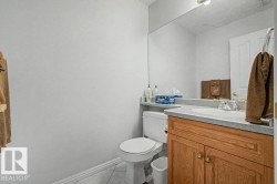 Bathroom featuring a wood-finish vanity with an integrated sink, a large wall-mounted mirror, and tile flooring - 