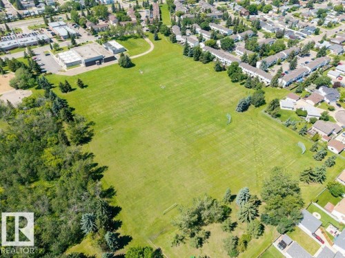 Expansive green space featuring manicured lawns, mature evergreen trees, and recreational goals - #39 2419 133 Av Nw, Edmonton, AB - Outdoor With View