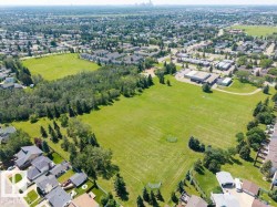 Expansive green space bordered by mature trees and established residential properties - 