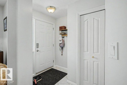 Entryway featuring white six-panel door with smart lock, flush-mount ceiling fixture, and bi-fold closet doors - #39 2419 133 Av Nw, Edmonton, AB - Indoor Photo Showing Other Room