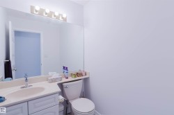 Bathroom vanity with an integrated sink and light-toned countertop, featuring white cabinetry and a large mirror with overhead vanity lighting - 
