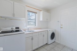 Laundry area featuring white cabinetry, a utility sink, countertop space, and tile flooring - 