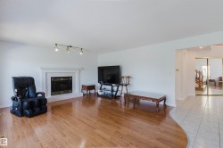 Spacious interior with hardwood-finish flooring and a white-painted fireplace featuring a stone surround - 