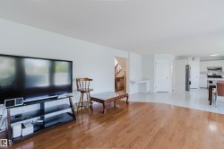 Open-concept living area with wood-finish flooring transitioning to tile - 