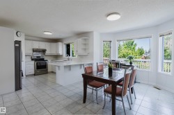 Spacious kitchen and dining area featuring white cabinetry, stainless steel appliances, a breakfast bar, and tile flooring - 