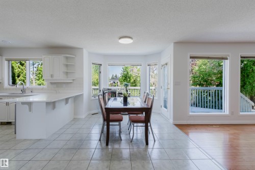 Open-concept dining area featuring a bay window, tile flooring, and direct access to an outdoor deck - 15 Cormack Crescent Nw, Edmonton, AB - Indoor