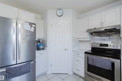 Bright kitchen featuring white cabinetry and stainless steel appliances - 