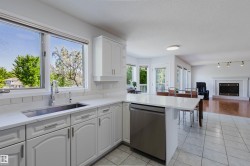 Kitchen featuring white cabinetry, light-toned countertops, an undermount stainless steel sink, and a stainless steel dishwasher - 
