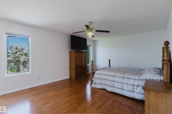 Spacious room featuring wood-finish flooring, white walls, and a window with exterior tree scenery - 