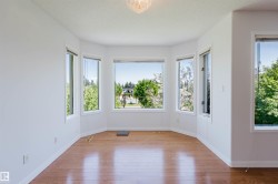 Bay window with multiple large glass panels, wood-finish flooring, white walls, and a ceiling-mounted light fixture - 