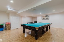 Spacious recreation area featuring light wood-finish flooring, recessed lighting, and white paneled doors - 