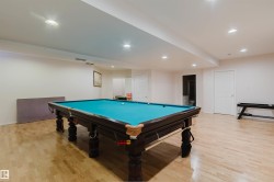 Spacious recreation area featuring light wood-finish flooring, recessed lighting, and multiple white paneled doors - 