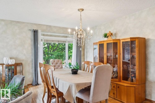 Dining area featuring wood-finish flooring, a bay window with natural light, and a crystal chandelier - 15804 80 Street Nw, Edmonton, AB - Indoor Photo Showing Dining Room