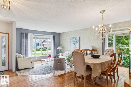 Dining area featuring a crystal chandelier, wood-finish flooring, and a sliding glass door - 15804 80 Street Nw, Edmonton, AB - Indoor Photo Showing Dining Room
