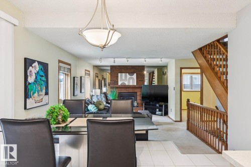 Spacious dining area with tile flooring, featuring an overhead chandelier and exposed ceiling beams - 15804 80 Street Nw, Edmonton, AB - Indoor