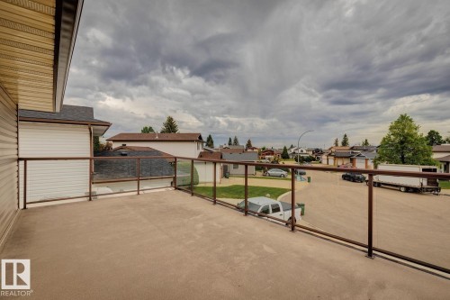 Expansive outdoor deck featuring a glass railing system and a textured surface, offering broad neighborhood views - 15804 80 Street Nw, Edmonton, AB - Outdoor