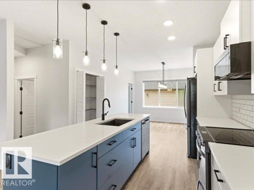 Kitchen featuring a large island with a dark blue base, white countertop, and integrated sink - 17487 77 Street, Edmonton, AB - Indoor Photo Showing Kitchen With Upgraded Kitchen