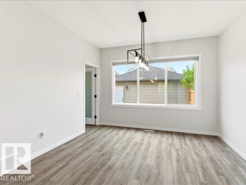 Spacious room featuring wood-finish flooring, white baseboards, and bright white walls - 17487 77 Street, Edmonton, AB - Indoor Photo Showing Other Room
