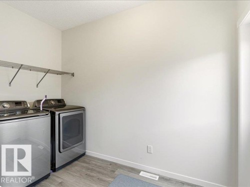 Dedicated laundry area featuring modern appliances, wire shelving, and wood-finish flooring - 17487 77 Street, Edmonton, AB - Indoor Photo Showing Laundry Room