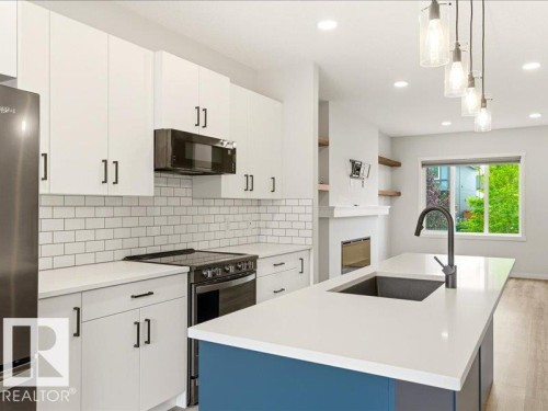 Contemporary kitchen featuring white cabinetry, subway tile backsplash, stainless steel appliances, and a central island with a sink and pendant lighting - 17487 77 Street, Edmonton, AB - Indoor Photo Showing Kitchen With Upgraded Kitchen