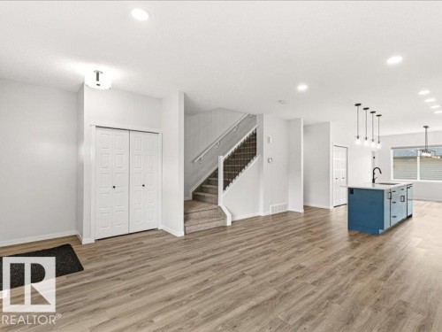 Open-concept living space with wood-finish flooring, a contemporary staircase, recessed lighting, and a modern kitchen island with a dark faucet - 17487 77 Street, Edmonton, AB - Indoor Photo Showing Kitchen